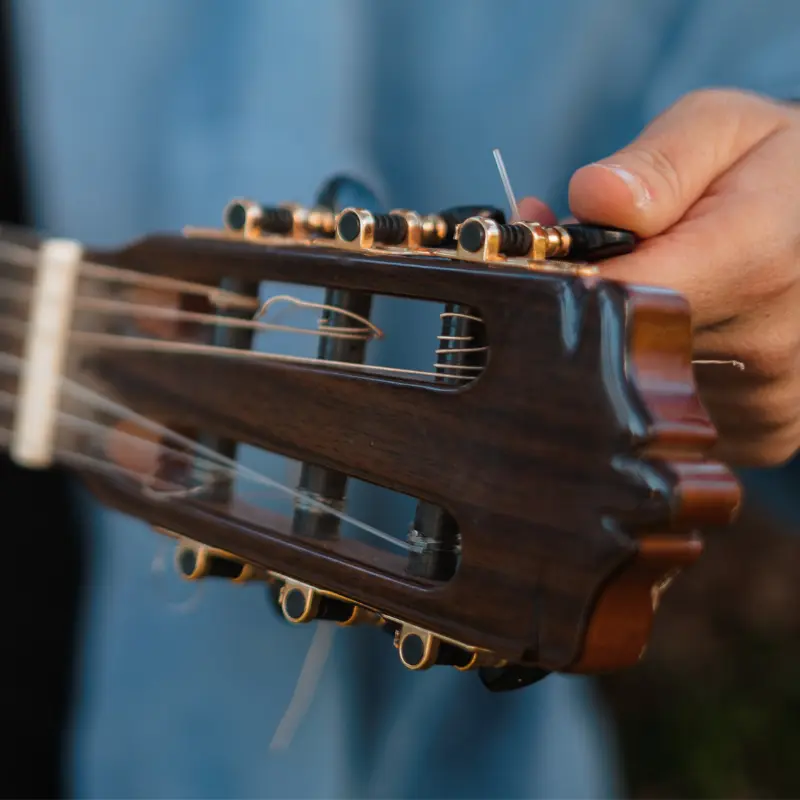 Persona ajustando las clavijas de una guitarra